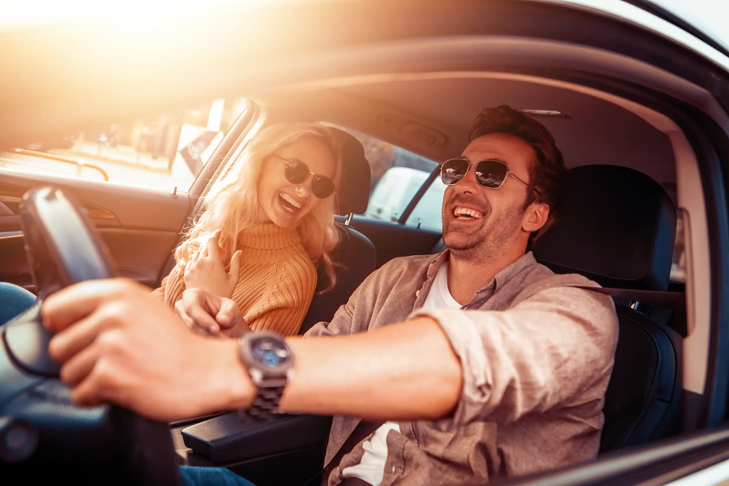 Una coppia felice durante un viaggio in auto, che si sorride a vicenda